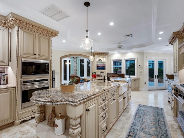 kitchen featuring built in microwave, french doors, stainless steel oven, sink, and a kitchen island with sink