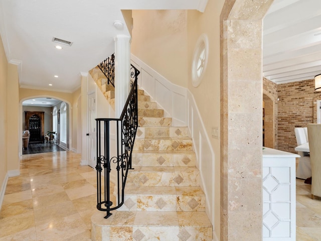 staircase featuring decorative columns and ornamental molding