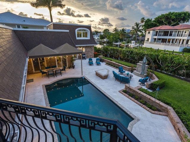 pool at dusk featuring a patio area and an outdoor hangout area