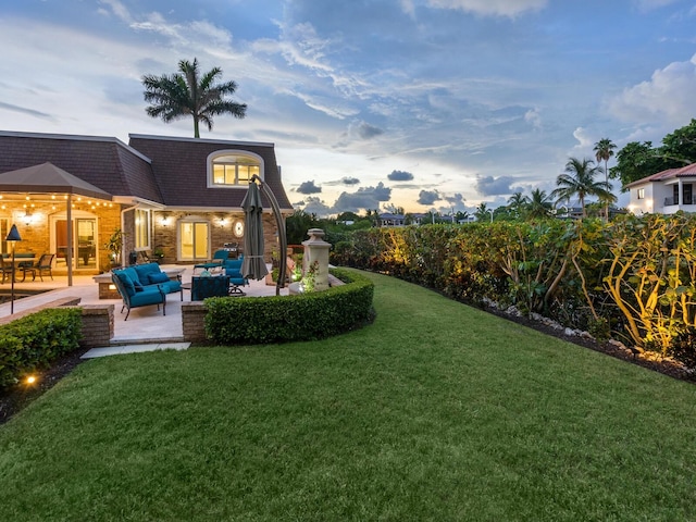 yard at dusk featuring an outdoor living space and a patio