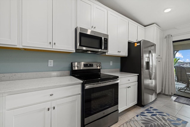 kitchen featuring light tile patterned flooring, white cabinets, light stone counters, and stainless steel appliances