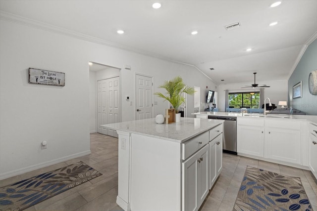 kitchen featuring vaulted ceiling, a kitchen island, stainless steel dishwasher, light stone countertops, and ceiling fan