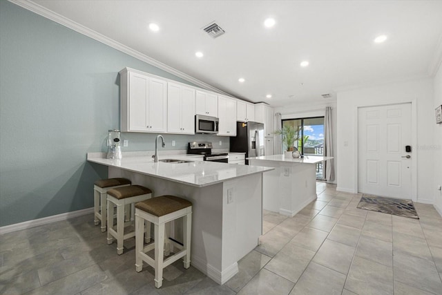 kitchen with appliances with stainless steel finishes, vaulted ceiling, sink, kitchen peninsula, and white cabinetry