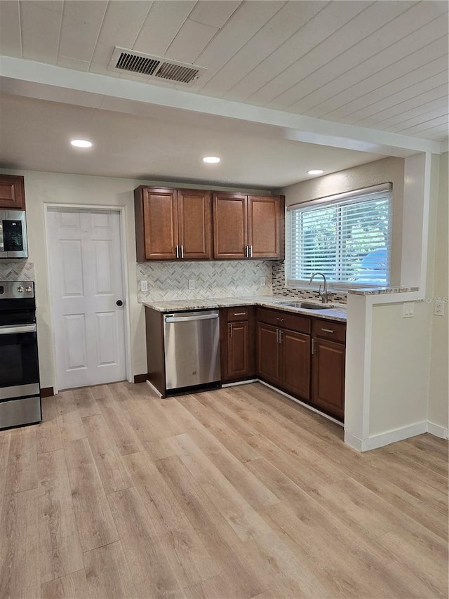 kitchen with sink, backsplash, appliances with stainless steel finishes, and light hardwood / wood-style floors