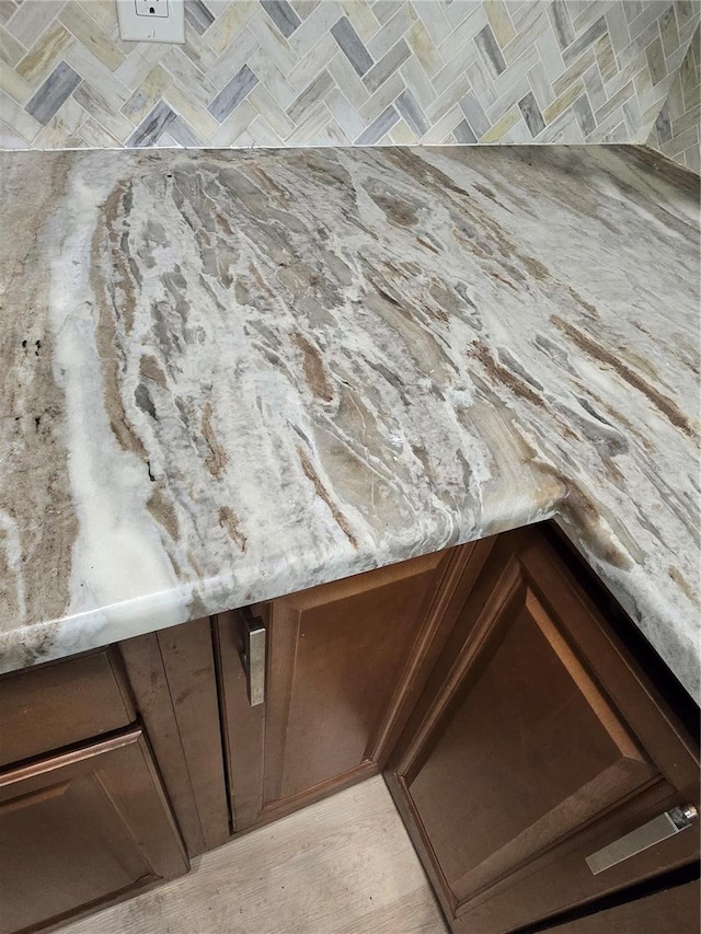 details featuring dark brown cabinetry and light stone counters