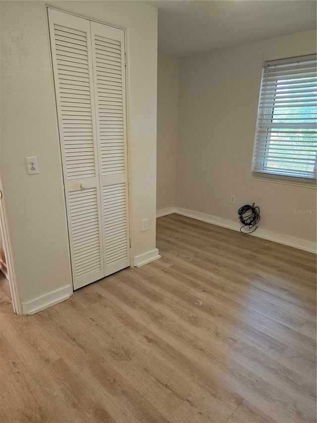 unfurnished bedroom with light hardwood / wood-style flooring and a closet