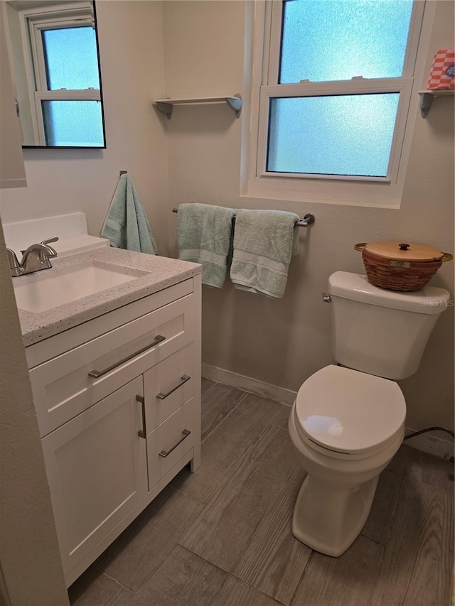 bathroom with hardwood / wood-style flooring, vanity, a wealth of natural light, and toilet