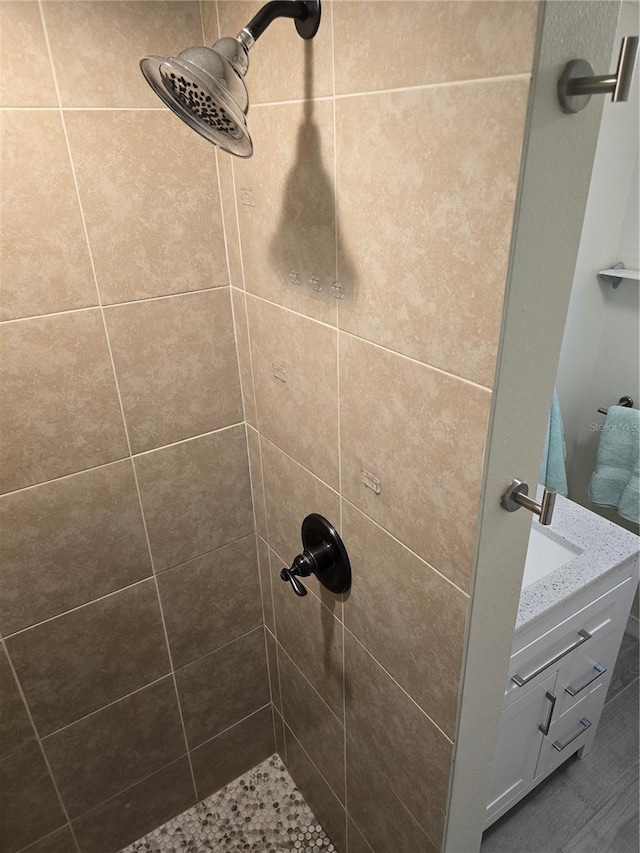 interior details with vanity and tiled shower