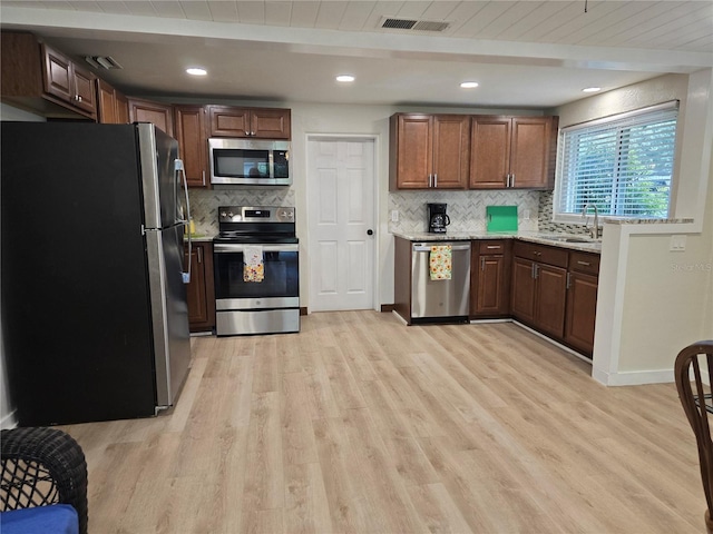 kitchen featuring stainless steel appliances, light hardwood / wood-style floors, light stone counters, and tasteful backsplash