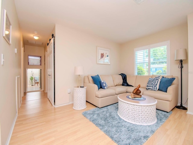 living room featuring a barn door and light hardwood / wood-style flooring