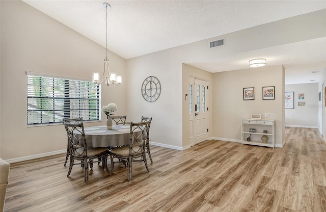 dining room featuring a notable chandelier, a textured ceiling, hardwood / wood-style flooring, and high vaulted ceiling