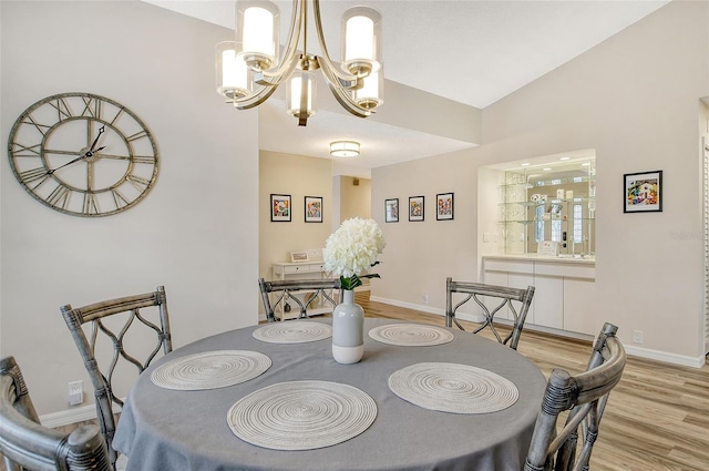 dining space with vaulted ceiling, light hardwood / wood-style flooring, and a notable chandelier