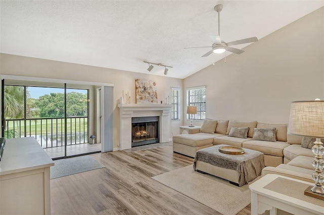 living room featuring light hardwood / wood-style floors, rail lighting, ceiling fan, and a healthy amount of sunlight