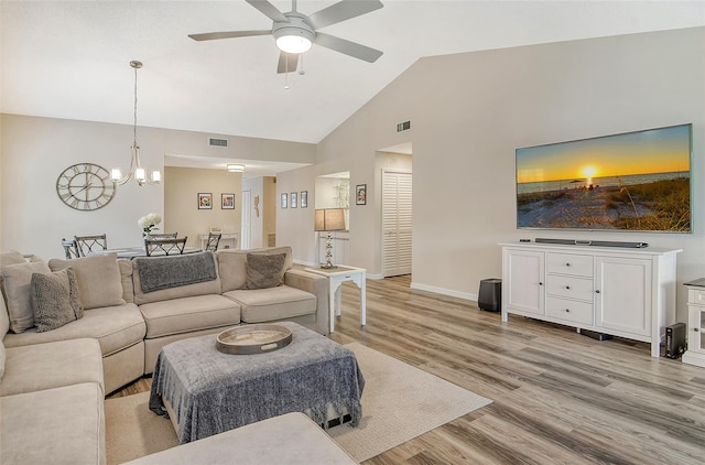 living room featuring high vaulted ceiling, ceiling fan with notable chandelier, and light hardwood / wood-style flooring