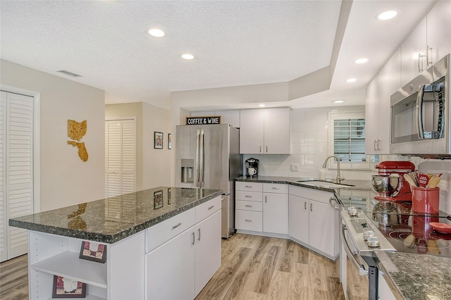 kitchen with sink, appliances with stainless steel finishes, light hardwood / wood-style flooring, and a center island