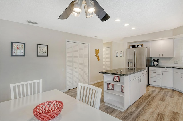 kitchen featuring ceiling fan, tasteful backsplash, white cabinets, a kitchen island, and light hardwood / wood-style flooring