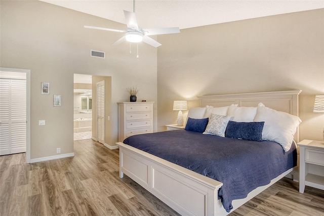 bedroom featuring light hardwood / wood-style floors, ensuite bathroom, high vaulted ceiling, and ceiling fan