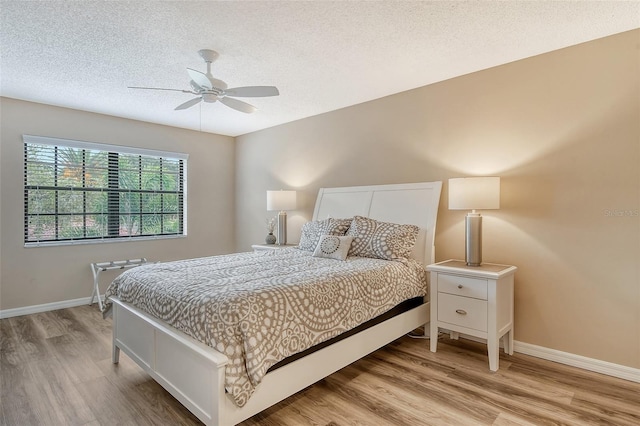 bedroom with a textured ceiling, light wood-type flooring, and ceiling fan