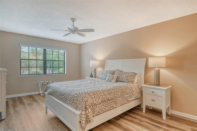 bedroom featuring light hardwood / wood-style flooring, a textured ceiling, and ceiling fan