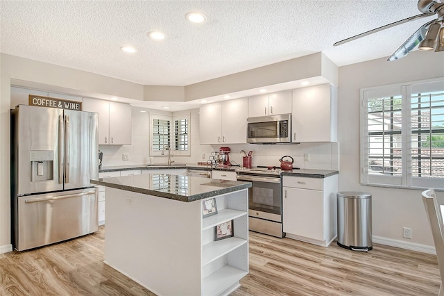 7673 Fairway Woods Dr Unit 706, Sarasota, FL 34238 - kitchen with a center island, a textured ceiling, open shelves, light wood-style floors, and appliances with stainless steel finishes