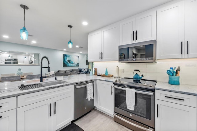 kitchen featuring hanging light fixtures, white cabinetry, appliances with stainless steel finishes, and sink