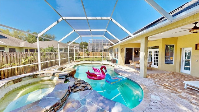 view of swimming pool with an in ground hot tub, ceiling fan, a patio area, and glass enclosure