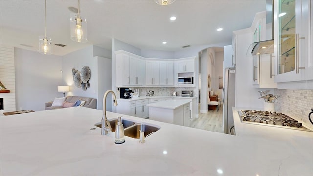 kitchen featuring pendant lighting, sink, appliances with stainless steel finishes, white cabinets, and a kitchen island