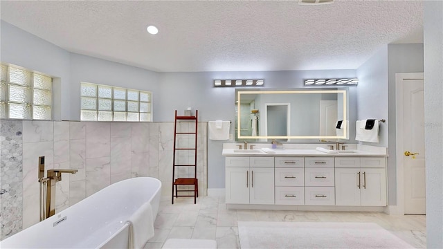 bathroom with vanity, a tub, tile walls, and a textured ceiling