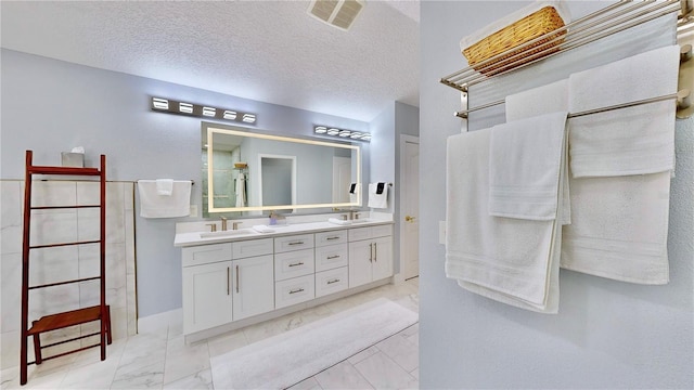 bathroom featuring vanity, a textured ceiling, and a shower