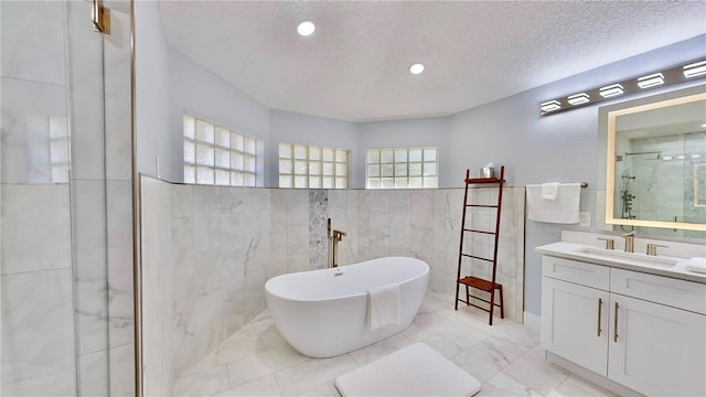 bathroom featuring vanity, plus walk in shower, a textured ceiling, and tile walls