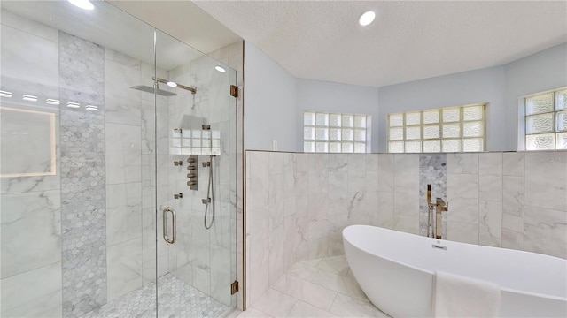 bathroom featuring shower with separate bathtub, tile walls, and a textured ceiling