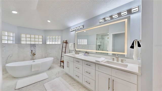 bathroom featuring vanity, a textured ceiling, and plus walk in shower