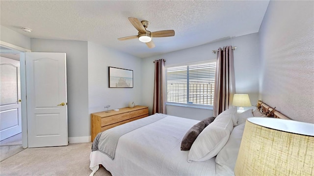 bedroom featuring ceiling fan, light colored carpet, and a textured ceiling