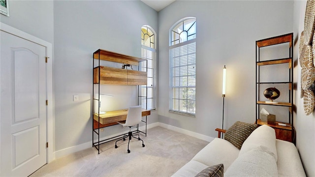 office area with a high ceiling and light colored carpet