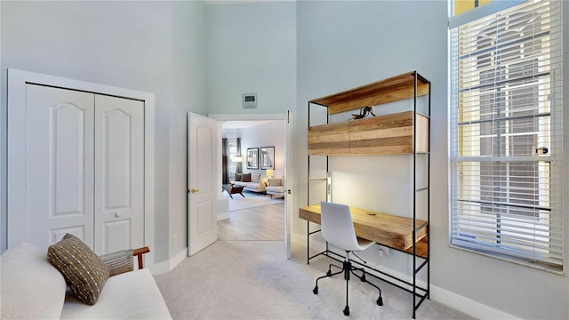 carpeted office featuring a high ceiling