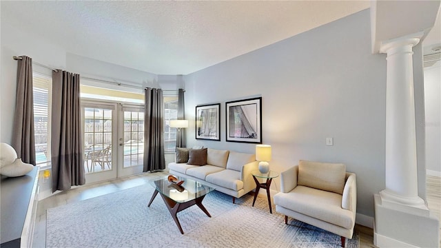 living room with decorative columns, french doors, and a textured ceiling