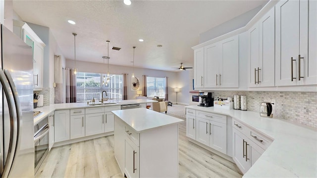 kitchen with pendant lighting, white cabinetry, sink, kitchen peninsula, and stainless steel appliances