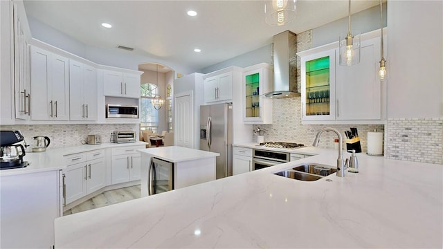 kitchen with hanging light fixtures, stainless steel appliances, sink, and white cabinets