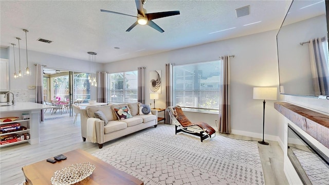 living room featuring sink, a textured ceiling, ceiling fan, and light hardwood / wood-style flooring