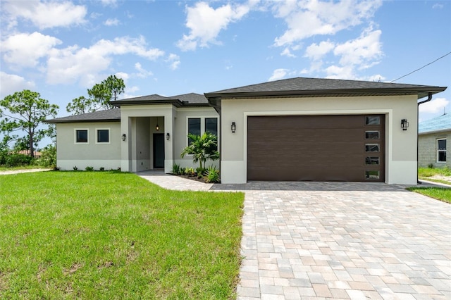 prairie-style house with a garage, decorative driveway, a front yard, and stucco siding