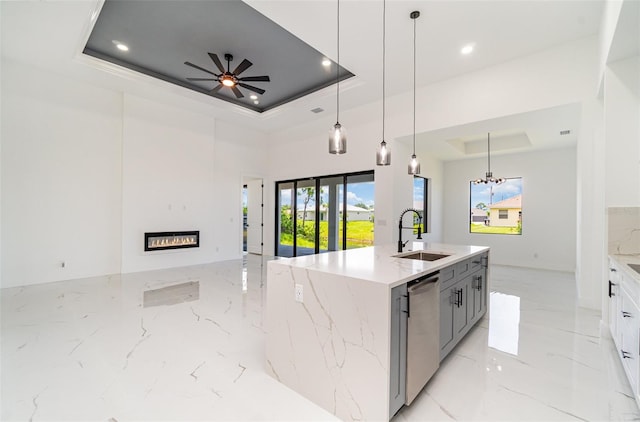 kitchen featuring ceiling fan with notable chandelier, light stone countertops, sink, and a tray ceiling