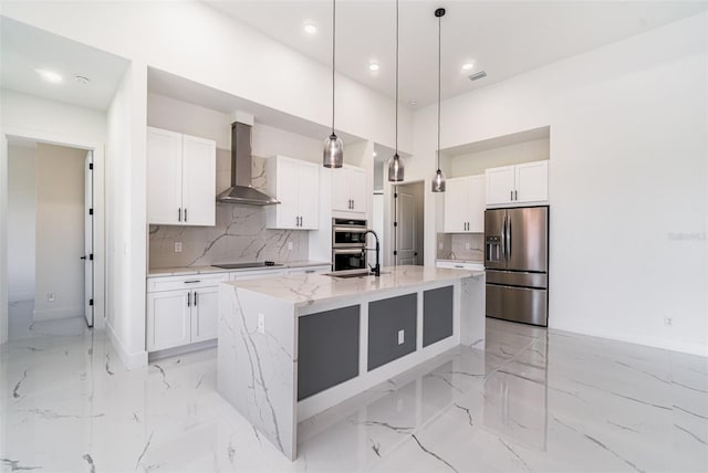 kitchen with decorative backsplash, stainless steel appliances, wall chimney exhaust hood, and an island with sink