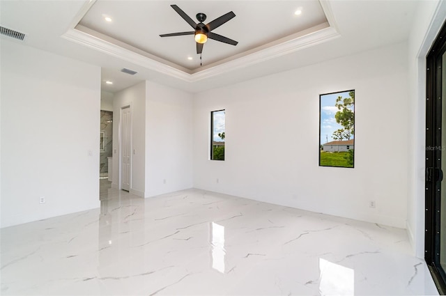 empty room with light tile patterned floors, ceiling fan, plenty of natural light, and a tray ceiling