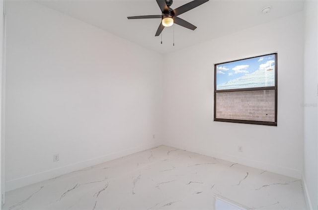 spare room featuring marble finish floor, baseboards, and a ceiling fan