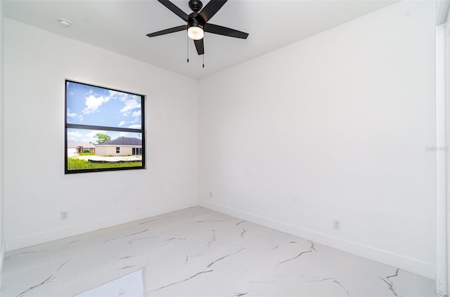 unfurnished room featuring ceiling fan, marble finish floor, and baseboards