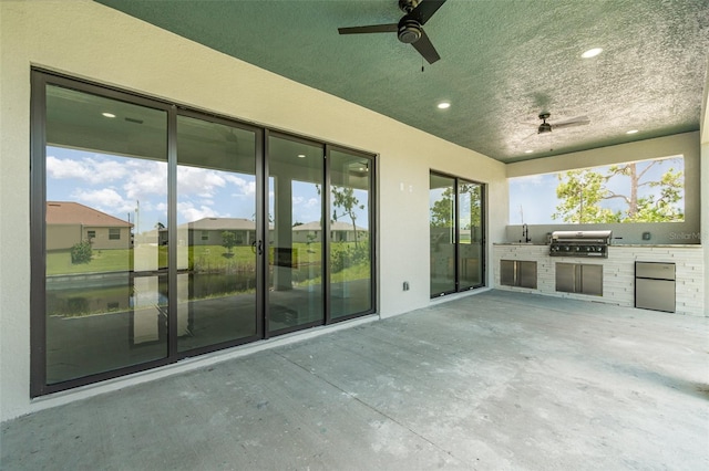 view of patio with grilling area, ceiling fan, and exterior kitchen