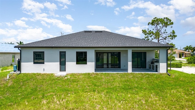 rear view of property featuring a yard, roof with shingles, a patio area, and stucco siding