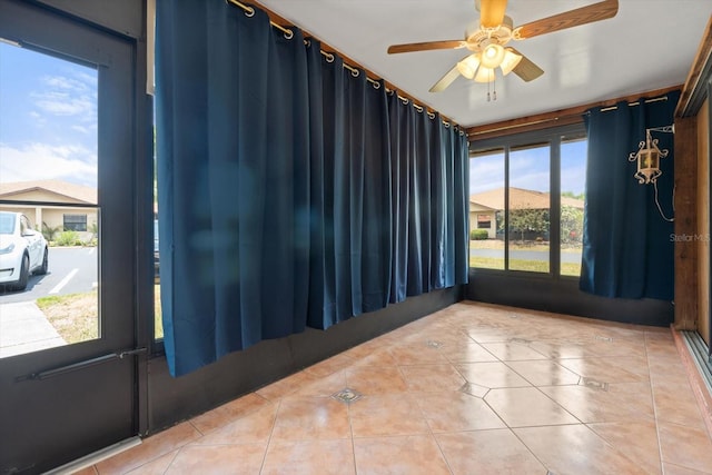 tiled empty room featuring ceiling fan