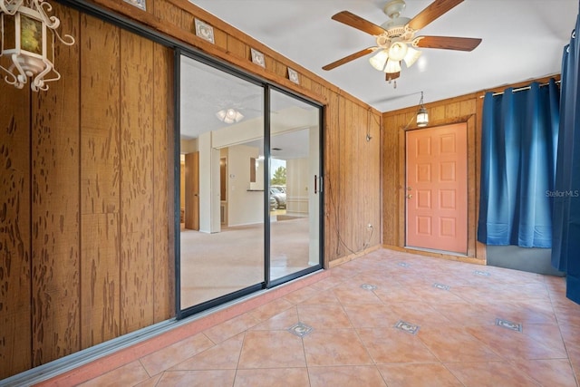 interior space featuring ceiling fan, tile patterned flooring, and wooden walls