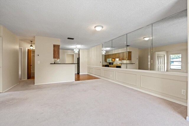 unfurnished living room featuring carpet and a textured ceiling